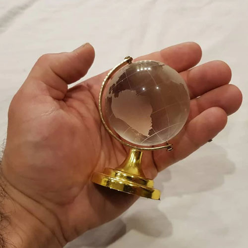  گوی کره زمین کریستالی پایه طلایی در دست 